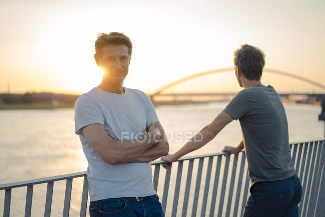 Deux amis regardant le coucher du soleil sur la rivière — Photo de stock
