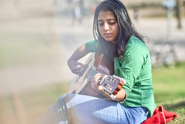 Giovane donna che suona la chitarra in un parco — Foto stock