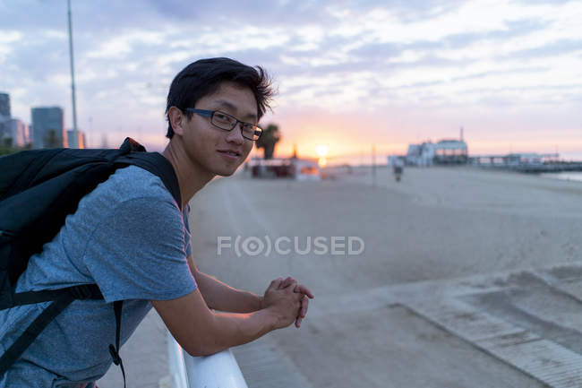 Молодой китаец с рюкзаком смотрит на пляж — стоковое фото