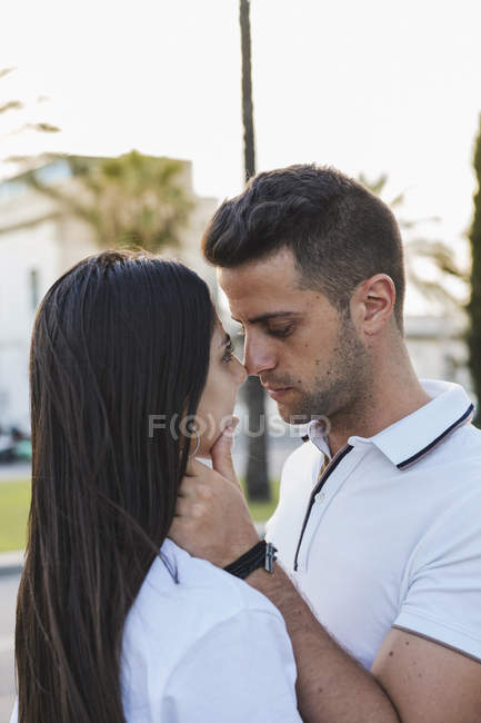 Giovane coppia romantica baciare su sfondo sfocato della città — Foto stock