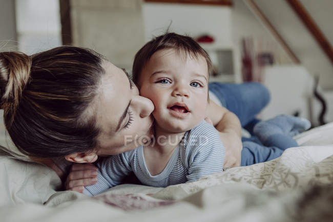 Mamma coccole bambino figlio a letto a casa — Foto stock