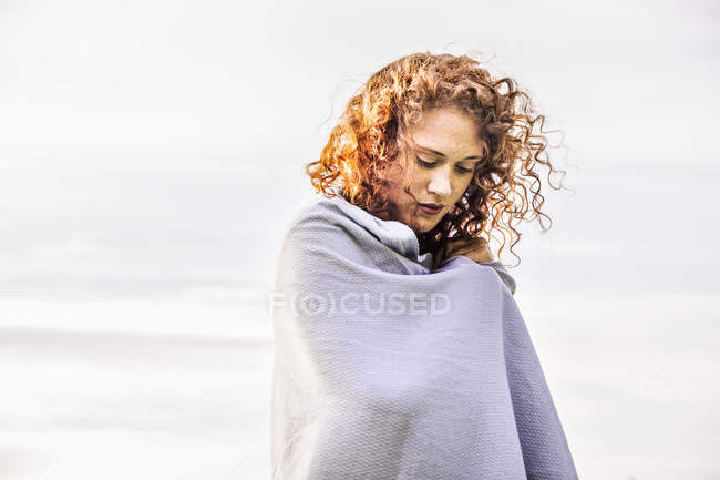Portrait of redheaded young woman wrapped in grey scarf — Stock Photo