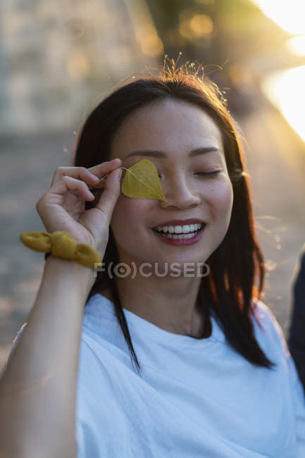 Ritratto di giovane donna felice che tiene la foglia davanti ai suoi occhi — Foto stock