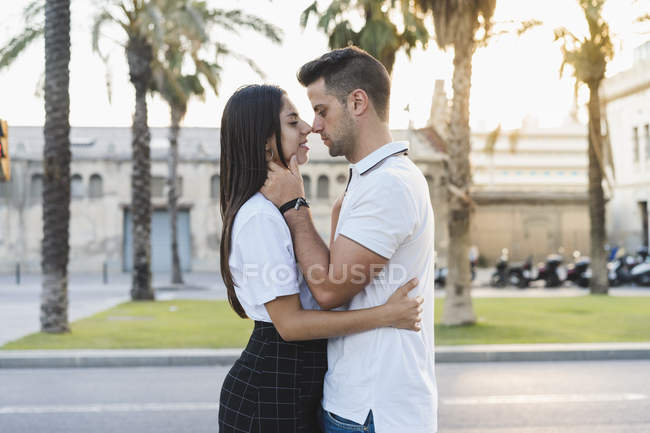 Jeune couple romantique embrasser sur fond flou de la ville — Photo de stock