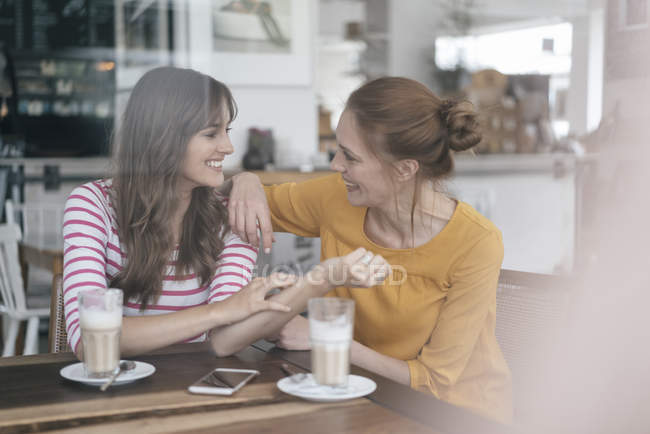 Due amiche che si incontrano in una caffetteria, parlano — Foto stock