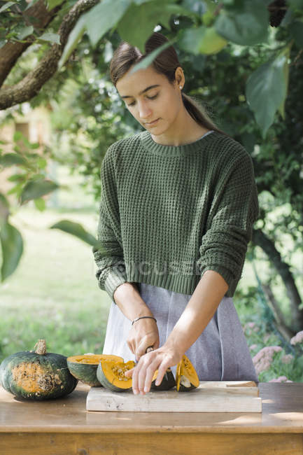 Молода жінка ріже гарбуз для приготування ґночі. — стокове фото