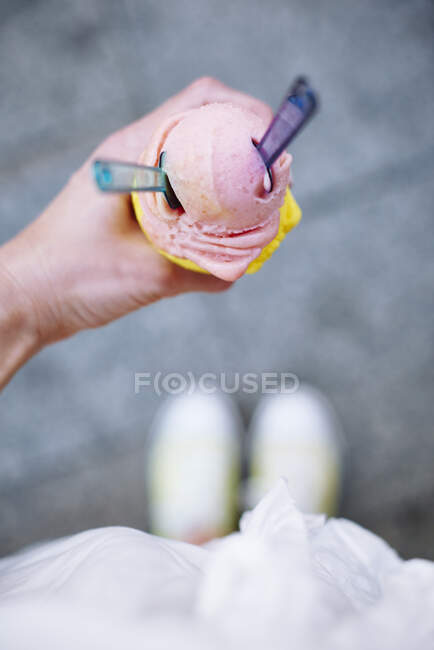 Mão de mulher segurando cone de sorvete com duas colheres e colheres — Fotografia de Stock