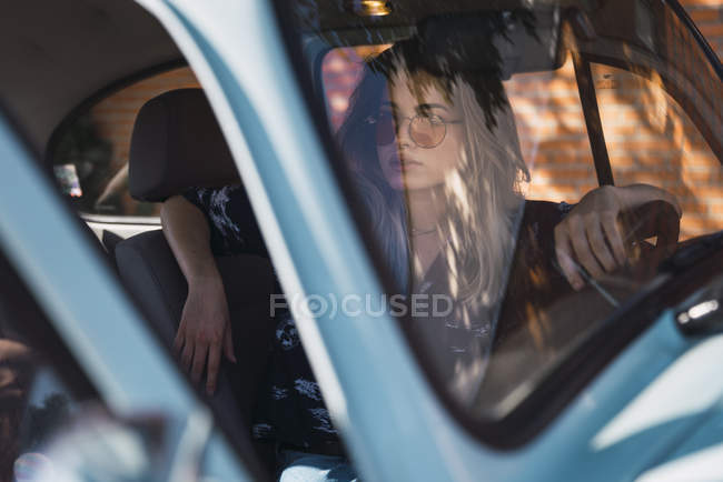 Молода жінка носить сонцезахисні окуляри і сидячи в машині — стокове фото