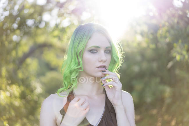 Retrato de mulher jovem com cabelo verde tingido e sobrancelhas no backlight — Fotografia de Stock