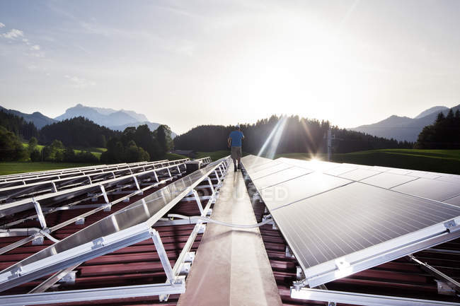 Austria, Tirol, Koessen, vista trasera de los trabajadores caminando en la planta solar por la noche - foto de stock