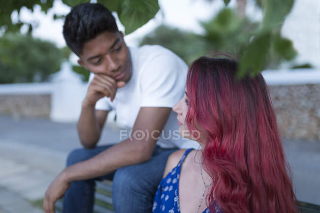 Jeune femme aux cheveux roux teints assise sur un banc avec son petit ami — Photo de stock