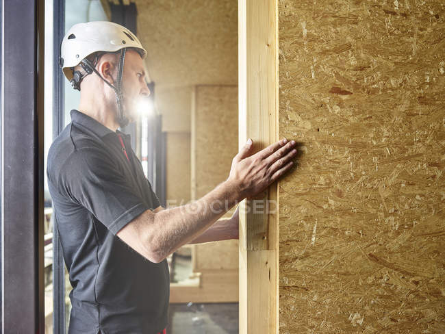Worker with helmet working with flakeboard — Stock Photo