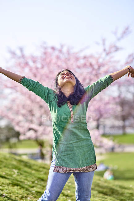 Happy young woman in a park at cherry blossom tree — Stock Photo