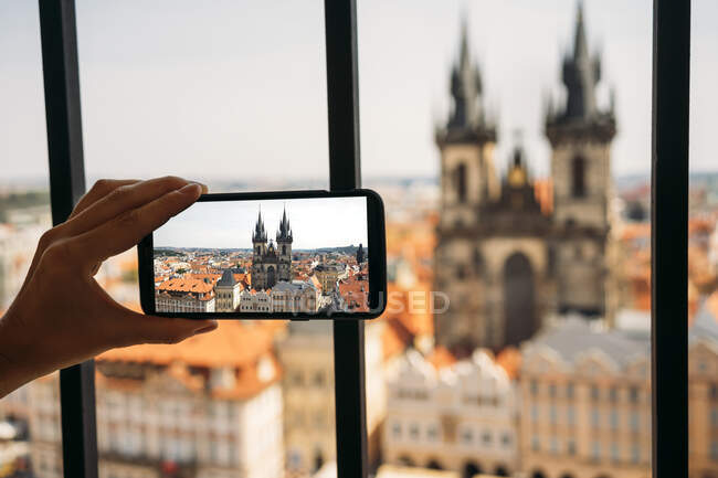 Czechia, Prague, woman taking photo of Church of Our Lady from old town hall with smartphone, partial view — Stock Photo