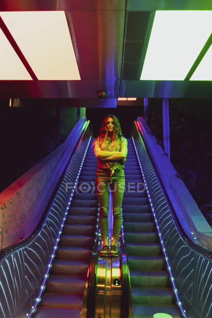 Портрет освітленої молодої жінки, що стоїть на перил ескалатора — стокове фото