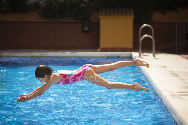 Little girl jumping head first into pool in summer — Stock Photo