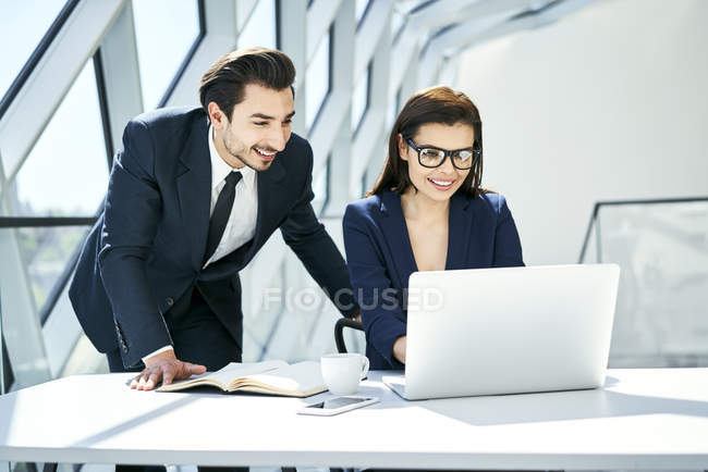 Femme d'affaires et homme d'affaires souriant utilisant un ordinateur portable au bureau dans un bureau moderne — Photo de stock