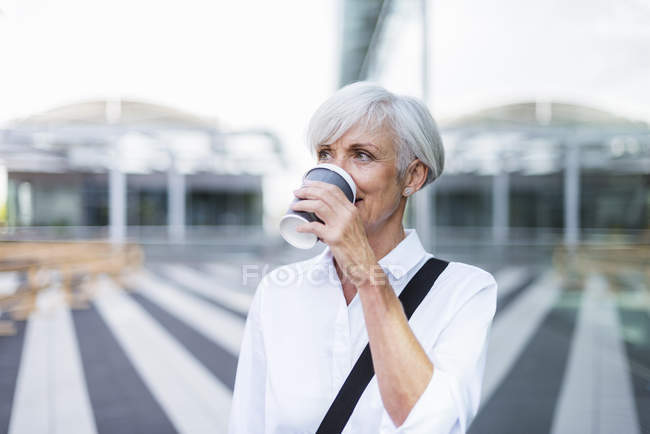 Senior businesswoman in city drinking coffee — Stock Photo