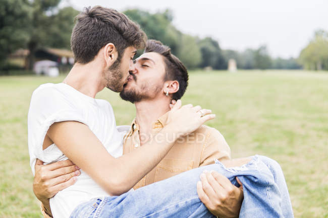 Beijar jovem gay casal relaxante no parque — Fotografia de Stock