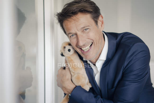Successful businessman holding cuddly toy — Stock Photo