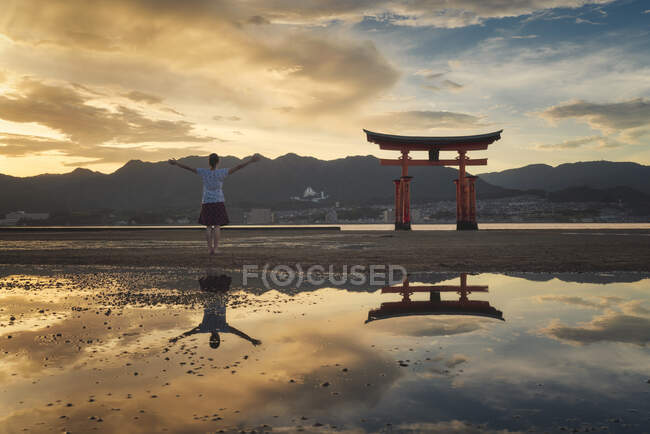 Mujer disfrutando de la puesta de sol en la isla de Itsukushima o Miyajima, Hiroshima, Japón - foto de stock
