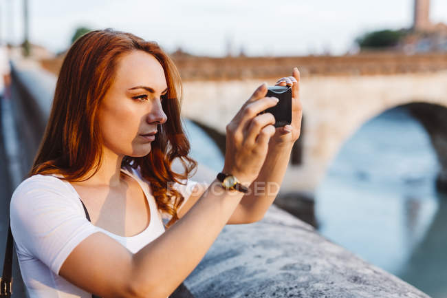 Italie, Vérone, femme rousse prenant des photos avec smartphone — Photo de stock