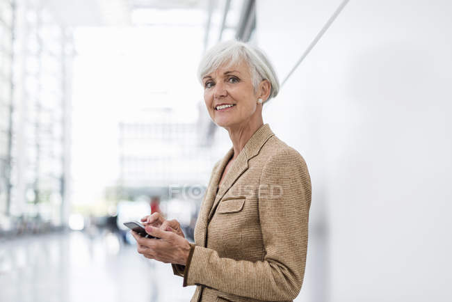 Retrato de mulher de negócios sênior sorridente usando telefone celular — Fotografia de Stock