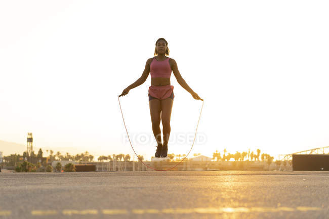 Spain, Barcelona, young black woman skipping rope at sunrise — Stock Photo
