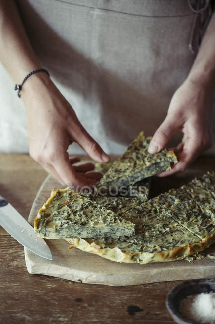 Giovane donna guarnire ceci fatti in casa e torta di erbe — Foto stock