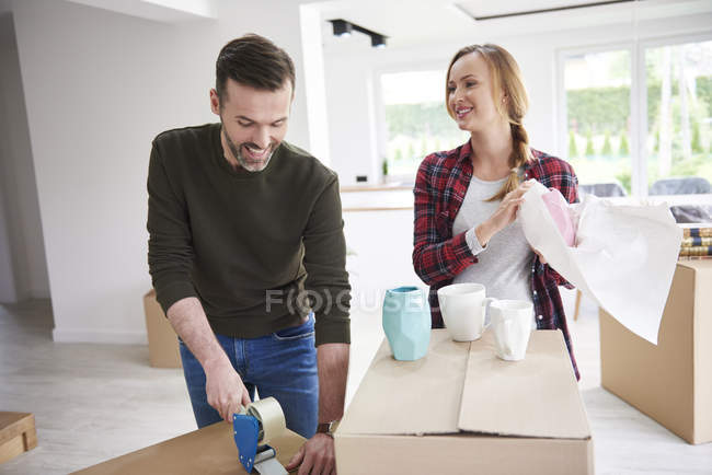 Couple moving house packing and taping cardboard boxes — Stock Photo