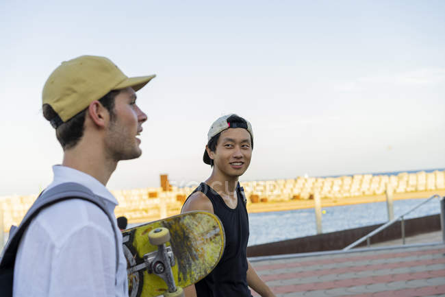 Due giovani uomini con lo skateboard in movimento parlando — Foto stock