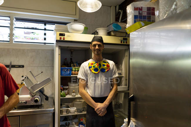 Portrait of funny pizza baker wearing clown bow tie in kitchen — Stock Photo