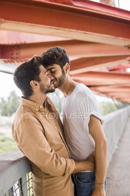 Молода гей-пара в любові цілується на пішохідному мосту — стокове фото