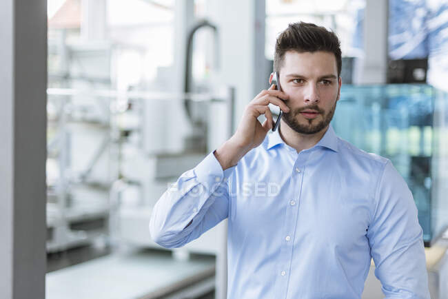 Retrato del hombre en el teléfono celular en fábrica - foto de stock