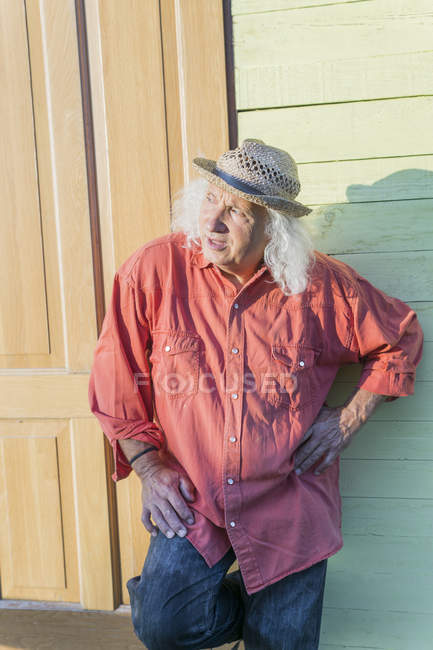 Homme âgé avec de longs cheveux gris portant un chapeau de paille et regardant de côté — Photo de stock