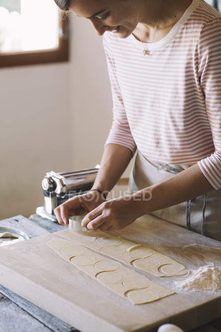 Frau bereitet Ravioli zu, Nudelteig auf Teigplatte ausschneiden — Stockfoto