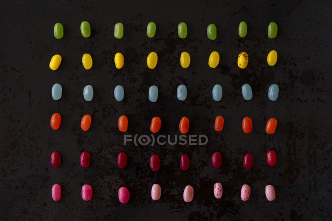 Размещение красочных конфет на черной земле — стоковое фото