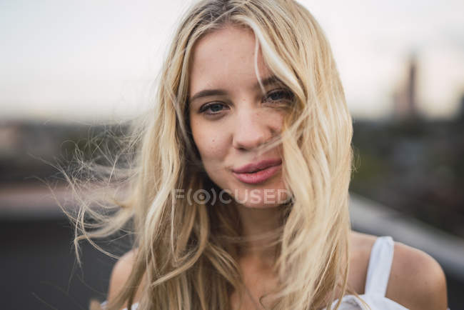 Portrait de jeune femme blonde souriante regardant la caméra, temps venteux — Photo de stock