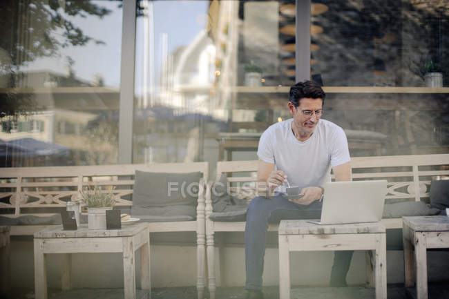 Geschäftsmann sitzt im Café, trinkt Kaffee, benutzt Laptop — Stockfoto