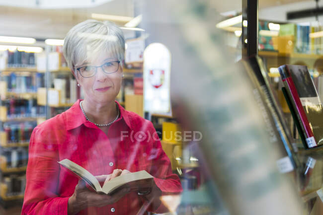 Портрет пожилой женщины за стеклом в городской библиотеке — стоковое фото