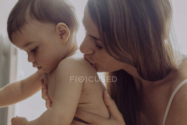 Primo piano di madre baciare bambino figlio spalla — Foto stock