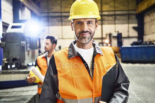 Портрет улыбающегося мужчины в защитной рабочей одежде на фабрике — стоковое фото