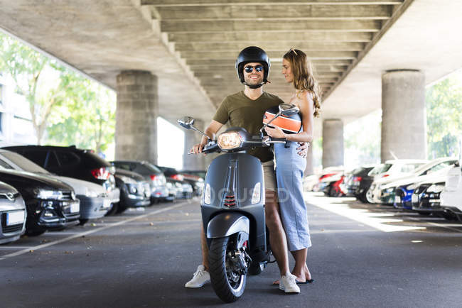 Happy couple with motor scooter at underpass — Stock Photo