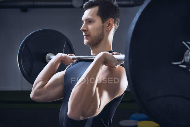 Мужчина делает пресс барбелл упражнения в тренажерном зале — стоковое фото