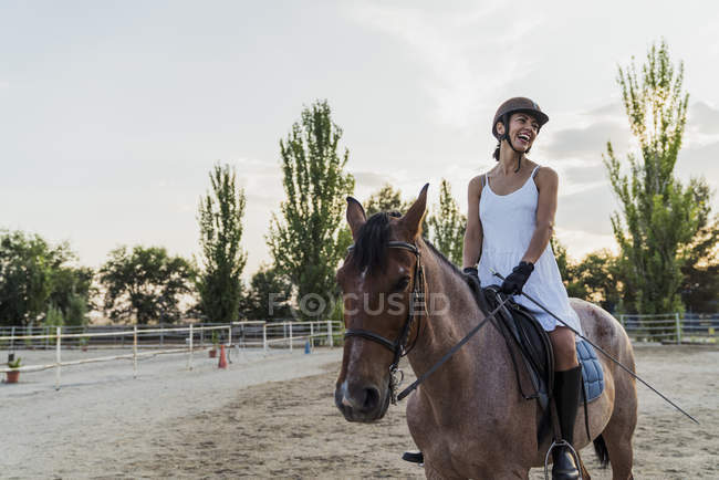 Mulher rindo no vestido e capacete no cavalo ao ar livre — Fotografia de Stock