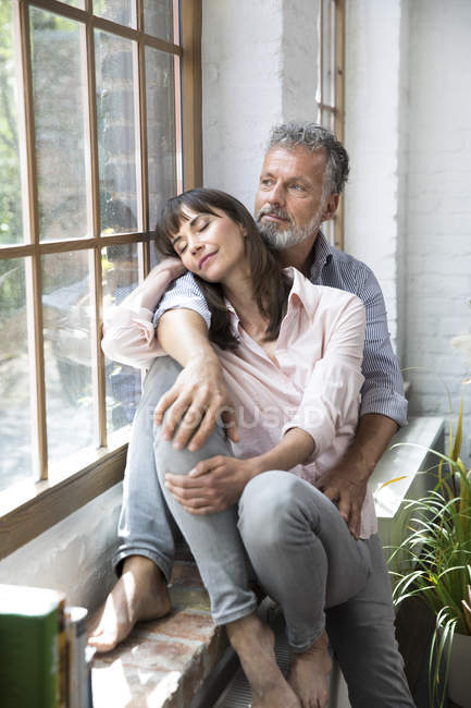 Couple âgé assis sur le rebord de la fenêtre, regardant par la fenêtre — Photo de stock