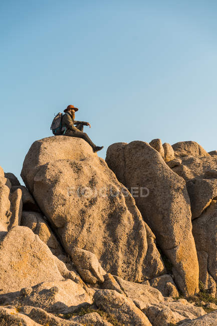 Italie, Sardaigne, randonneur avec chapeau et sac à dos reposant sur un rocher — Photo de stock