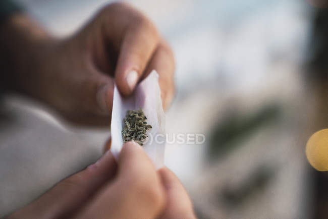 Hands of man rolling joint on blurred background — Stock Photo