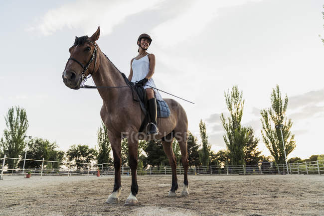 Sorrindo mulher no vestido e capacete no cavalo no anel de equitação — Fotografia de Stock