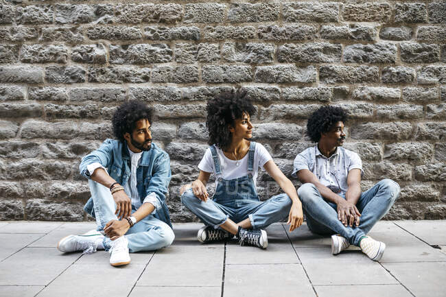 Tre amici seduti insieme a terra a guardare qualcosa — Foto stock